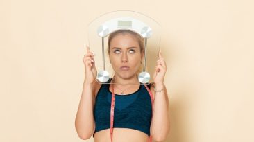 front view young female sport outfit holding scales light white wall fit sport beauty body health exercises